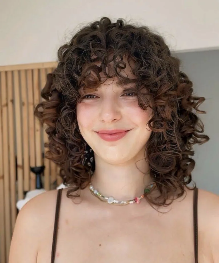 Cliente jovem sorridente com cabelo cacheado curto e definido